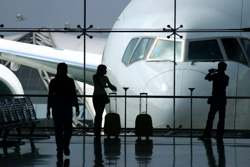 three silhouetted figures standing in an airport waiting lounge